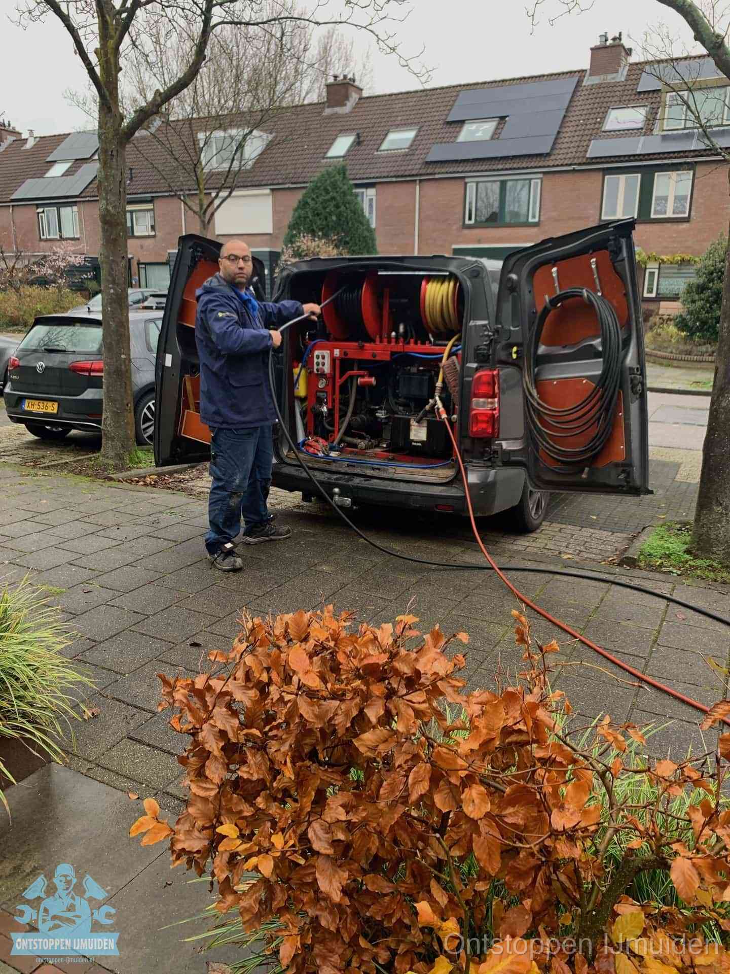 Monteur met rioolreinigingsbus levert rioolservice in de wijk in IJmuiden