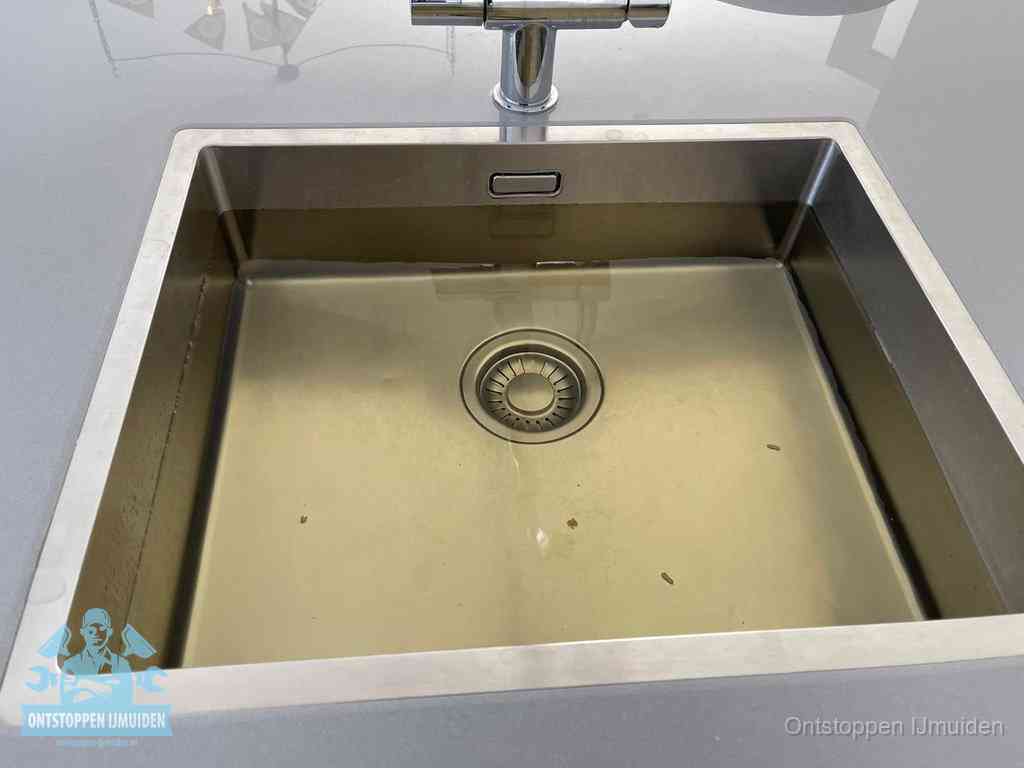 Stilstaand water in een rvs spoelbak dat niet wegloopt, een duidelijk signaal van een gootsteenverstopping in IJmuiden