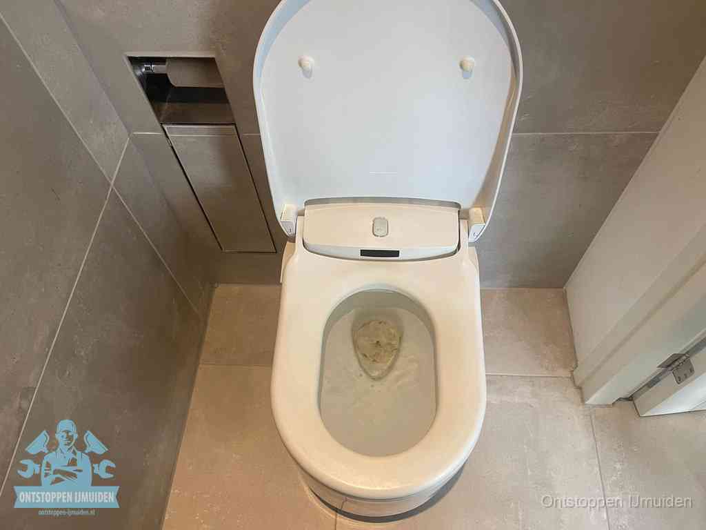 Een wit hangtoilet waarin een prop wc-papier op het water blijft drijven, een duidelijk signaal van een verstopte wc in IJmuiden