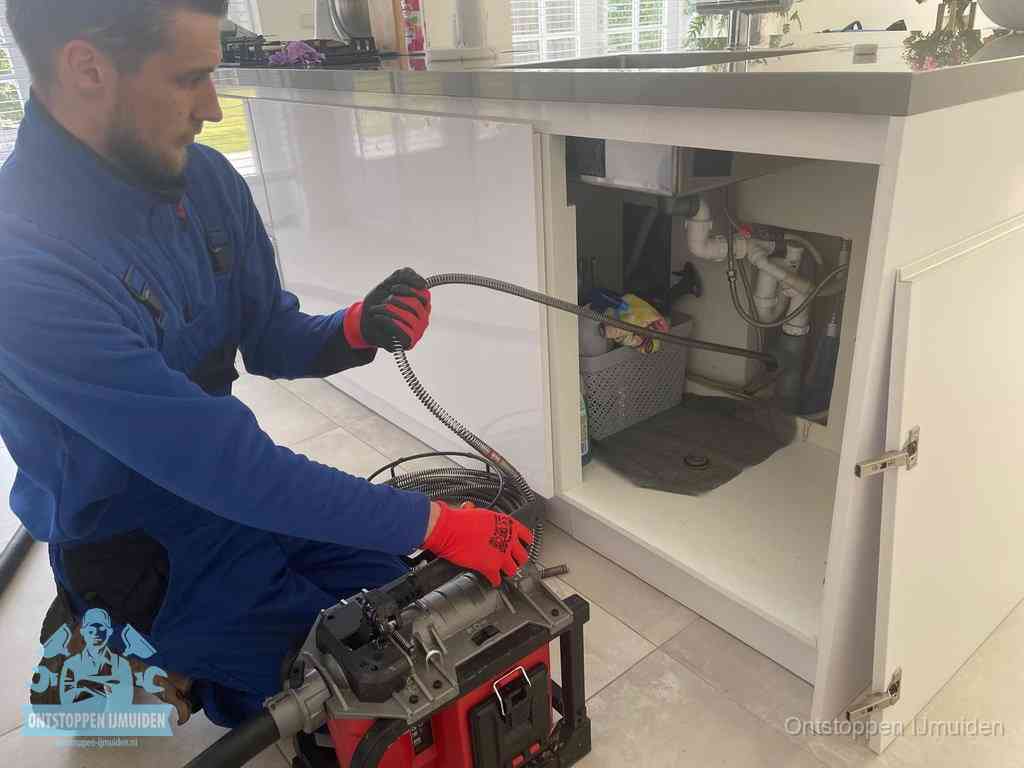 Een monteur reinigt de keukenafvoer grondig met een veermachine om terugkerende gootsteenverstoppingen te voorkomen in IJmuiden
