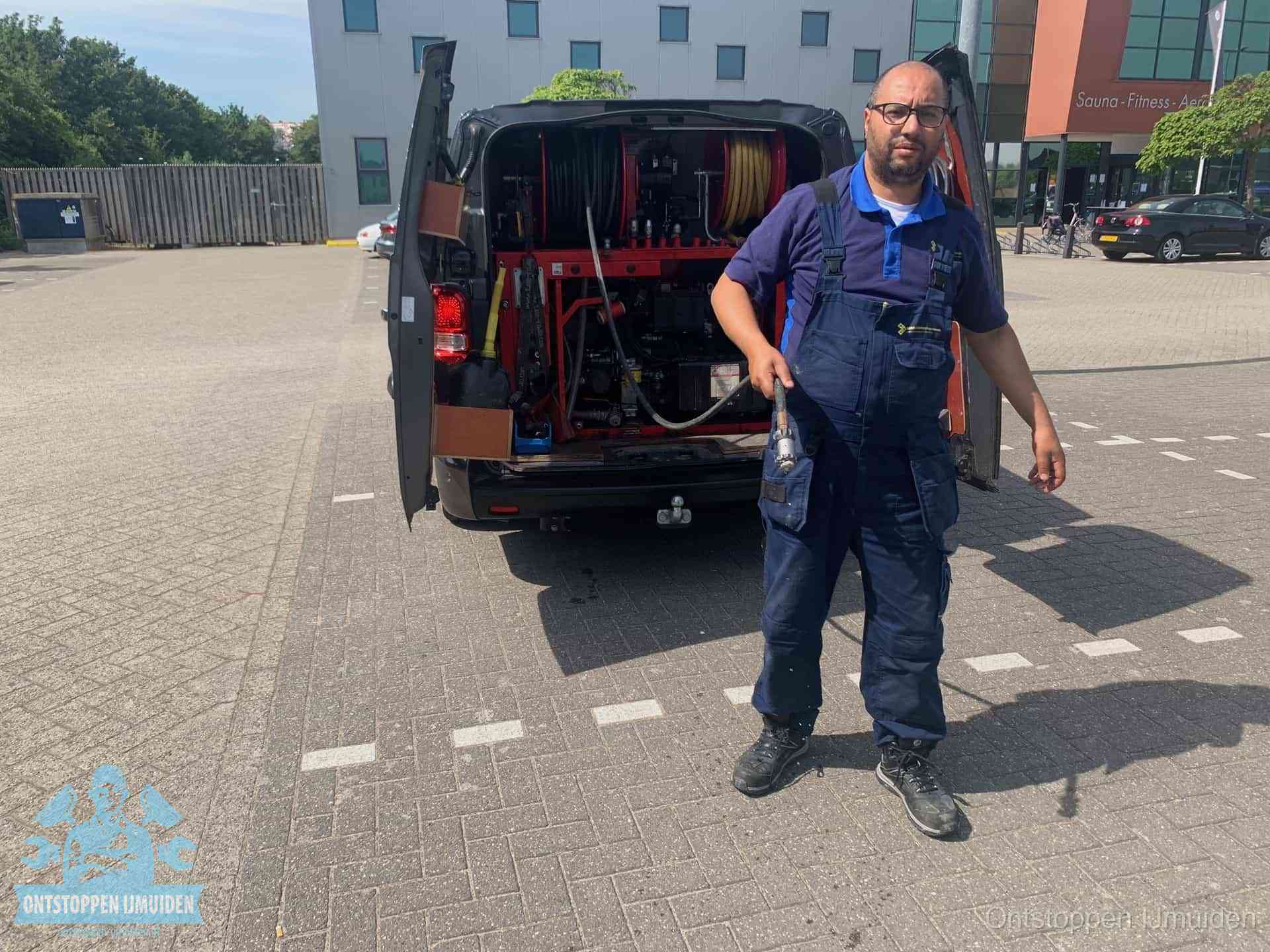 Een monteur bij zijn bestelbus met een hogedruk- en rioolreinigingsunit, klaar om de oorzaak van terugkerende wc-verstoppingen aan te pakken in IJmuiden