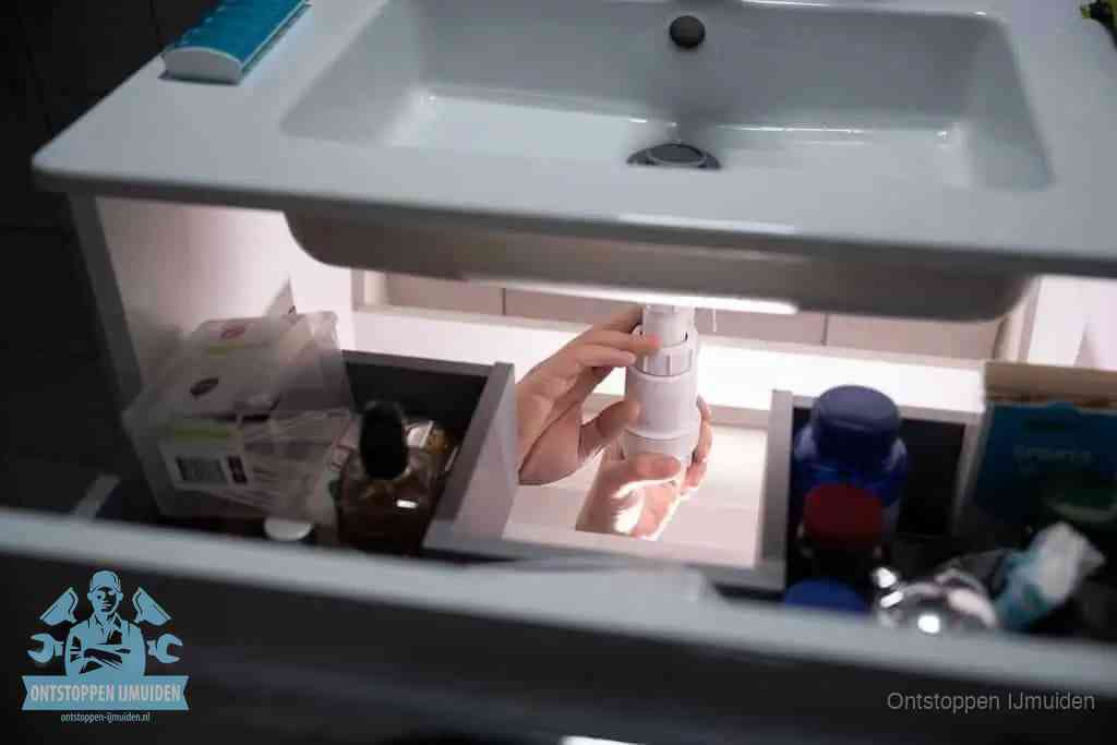 Een pompfles met zeep boven een wastafel in de toiletruimte, de warm water en afwasmiddel-methode om de wc te ontstoppen in IJmuiden