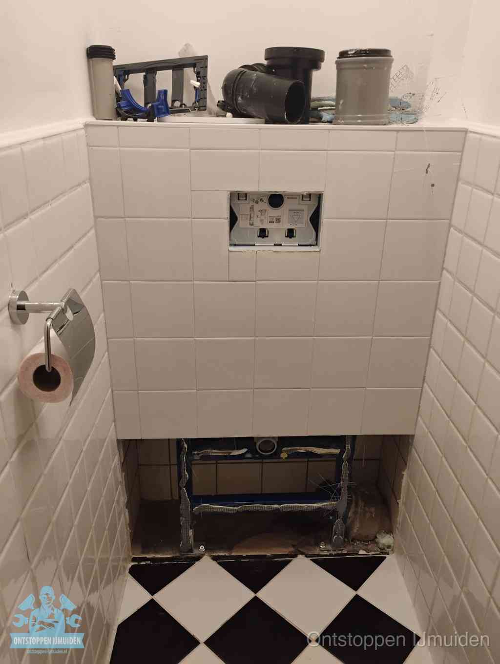 Een toiletruimte waar het hangtoilet en de inbouwreservoir-onderdelen zijn vrijgelegd voor onderhoud, periodiek nazicht voorkomt een wc-verstopping in IJmuiden