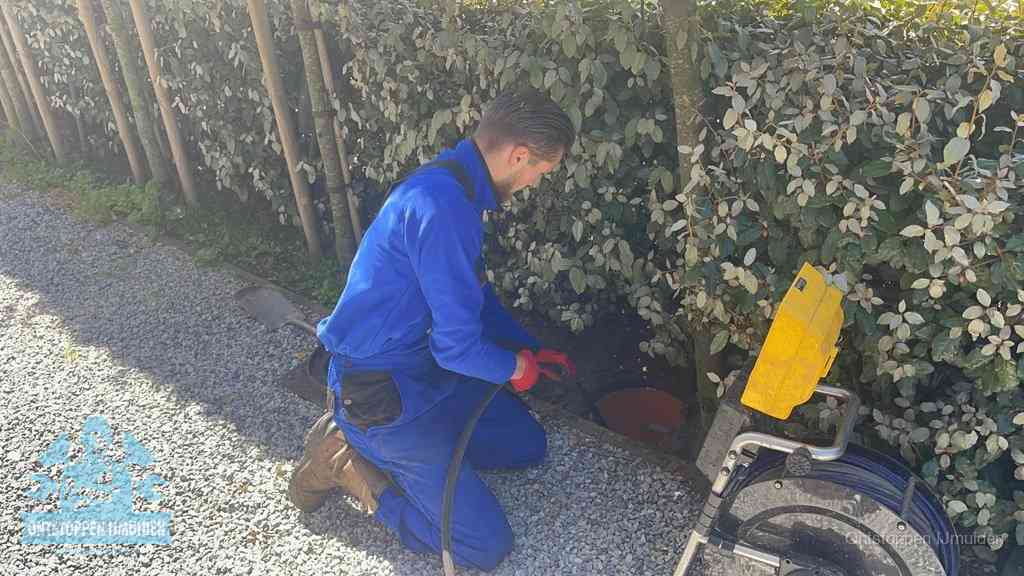 Monteur aan het werk bij een rioolput, de werkwijze voor riool ontstoppen in IJmuiden