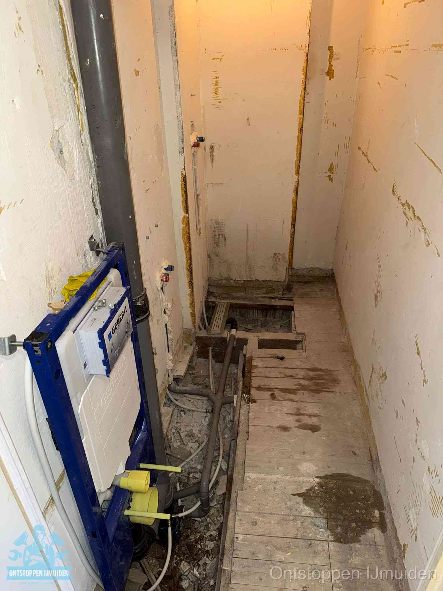 Een opgebroken toiletruimte tijdens renovatie met een Geberit inbouwreservoir en blootliggende oude afvoerleidingen, typisch voor oudere woningen in IJmuiden